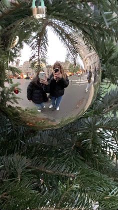 a woman taking a selfie in a christmas ornament on a pine tree