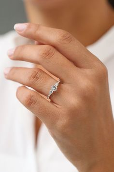 a woman's hand with a diamond ring on her left hand, wearing a white shirt