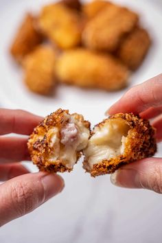 two hands holding up some food on a plate