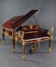 an ornately decorated grand piano with gold trimmings and red paint on it