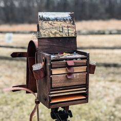 an old wooden box with many drawers on it's tripod in front of a fence