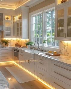 a kitchen with marble counter tops and white cabinets, along with lights on the windows