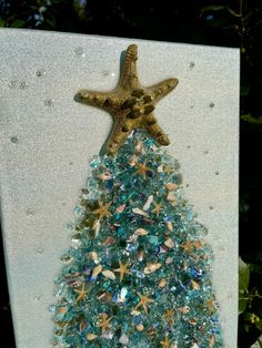 a christmas tree made out of glass beads and starfishs on a white board