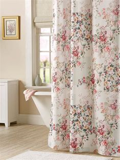 a bath tub sitting next to a window covered in curtains and rugs with flowers on them