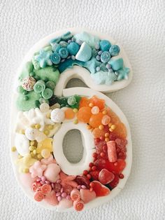 the number six is made out of plastic buttons and other colorful objects, including gummy bears