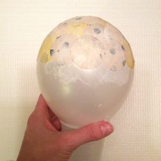 a hand holding a large white ball with blue dots on the outside and yellow spots on the inside