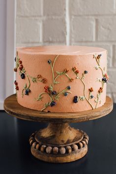 a pink cake decorated with flowers on a wooden stand