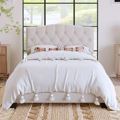 a bed with white sheets and pillows in a room