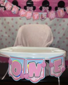 a baby's first birthday centerpiece with minnie mouse decorations on the top and pink polka dot bunting