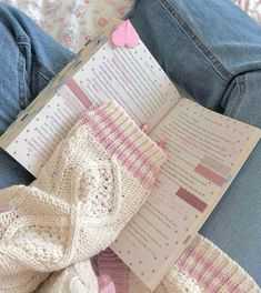 an open book sitting on top of a person's lap next to a pair of jeans