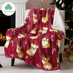 a blanket that is on top of a chair in front of a fire place and christmas tree