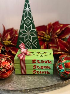 a stack of books sitting on top of a metal tray next to christmas ornaments and a tree