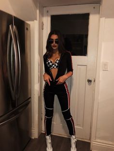 a woman standing in front of a refrigerator wearing sunglasses and checkered cropped top