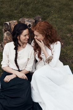 two women sitting next to each other on the grass