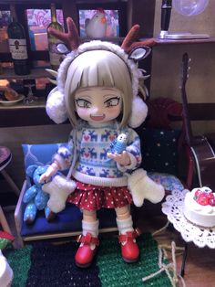 a doll sitting on top of a chair next to a cake