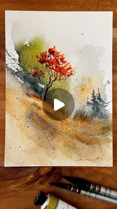 a watercolor painting on paper with paintbrushes next to it and an image of a tree in the background