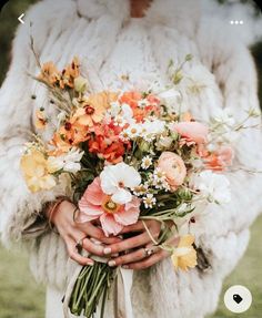 a woman wearing a fur coat holding a bouquet of flowers in front of her face