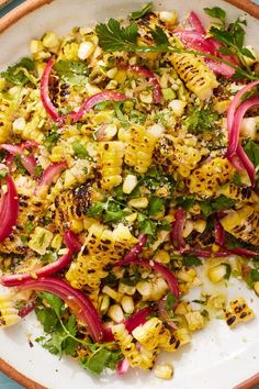 a white bowl filled with corn, radishes and cilantro on top of a blue table