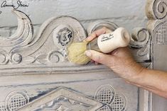 a hand is holding a brush to paint an ornate door