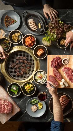 people are preparing food at a table with chopsticks and tongs on it