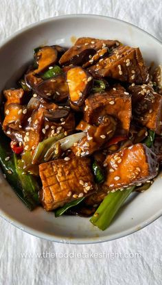 a white bowl filled with tofu and veggies on top of a table