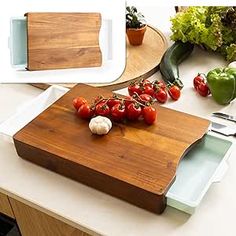 a cutting board with tomatoes and garlic on it next to other kitchen utensils