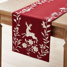 a red table runner with white flowers and deer on it