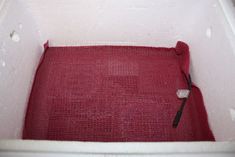 an empty bathtub with a red mat and black brush in the bottom corner,