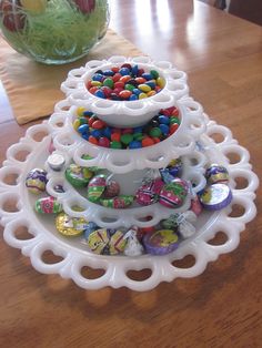 a white plate topped with lots of candies on top of a wooden table next to a vase filled with flowers