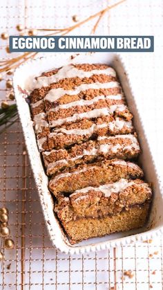 a loaf of cinnamon bread with icing in a white dish next to some sprigs