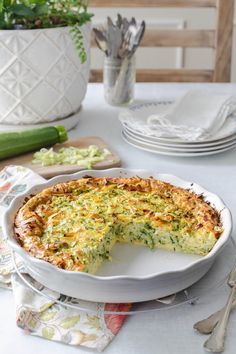 a quiche on a plate with a piece missing from it and other dishes in the background