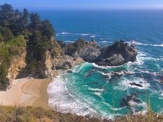 an ocean view from the top of a hill with rocks and trees in the foreground