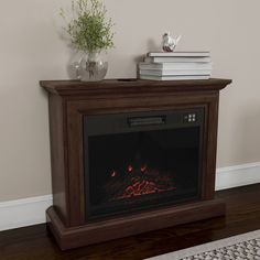 an electric fireplace in a living room with books on the table and a vase filled with flowers