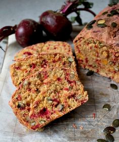 a loaf of fruit bread sitting on top of a cutting board next to two cherries