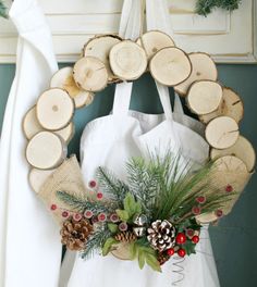 a wreath made out of tree slices and pine cones is hanging on the wall next to a white bag