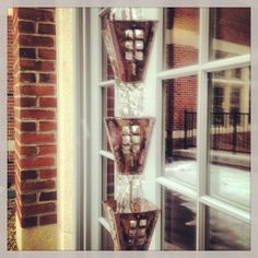 three glass vases sitting on top of a window sill in front of a brick building