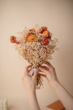 a person holding a bouquet of flowers over their face with both hands on top of it