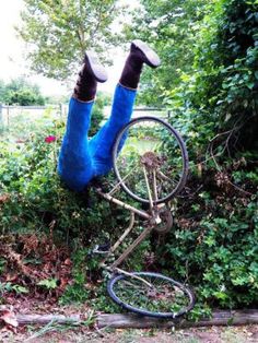 a person laying upside down on the ground with their feet up in the air and holding onto an old bicycle wheel