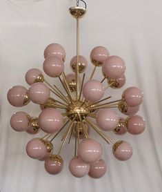 a pink and gold chandelier hanging on a white wall in a living room