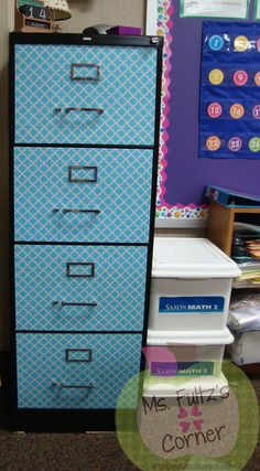 a blue filing cabinet sitting in front of a bulletin board