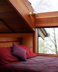 a bed sitting under a window next to a wooden headboard