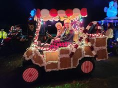 an old man and woman are riding in a decorated car with lights on the roof