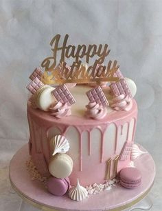 a pink and white birthday cake sitting on top of a table