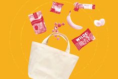 a white bag filled with candy, bananas and other items on top of an orange background