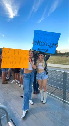 two women holding up signs while standing on a deck