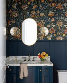 a bathroom with blue cabinets and floral wallpaper