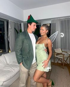 a man and woman dressed up as tinkerbells standing in a living room