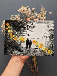 a person holding up a card with yellow flowers on it and two people in the background