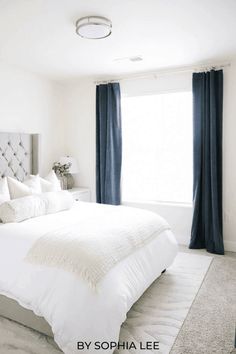 a bedroom with white bedding and blue drapes