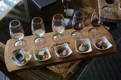 several wine glasses are lined up on a wooden tray